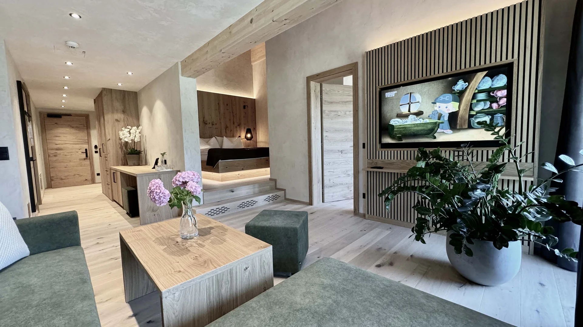Moderner Hotelzimmer-Wohnbereich mit grüner Couch und Holzdetails