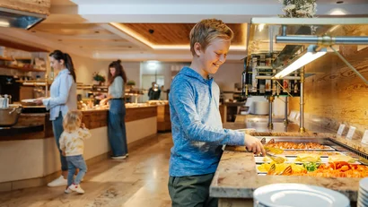 Junge wählt Essen an einem Buffet in einem Restaurant aus