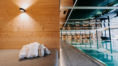 Wellnessbereich mit Pool, Holzverkleidung, Bademantel und Hausschuhen