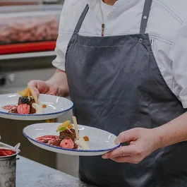 Koch trägt zwei Teller mit kunstvoll angerichteten Desserts