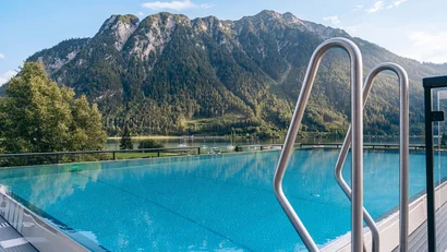 Infinity-Pool mit Blick auf Berge und See bei klarem Himmel