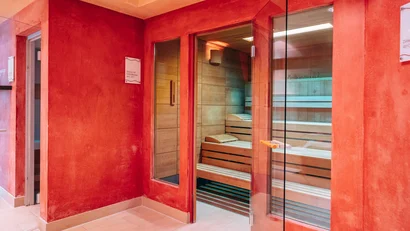 Moderner Saunaraum mit Holzbank und roter Wandfarbe