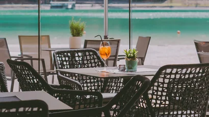 Leeres Cafétisch mit Getränk und Pflanzen, Blick auf einen See