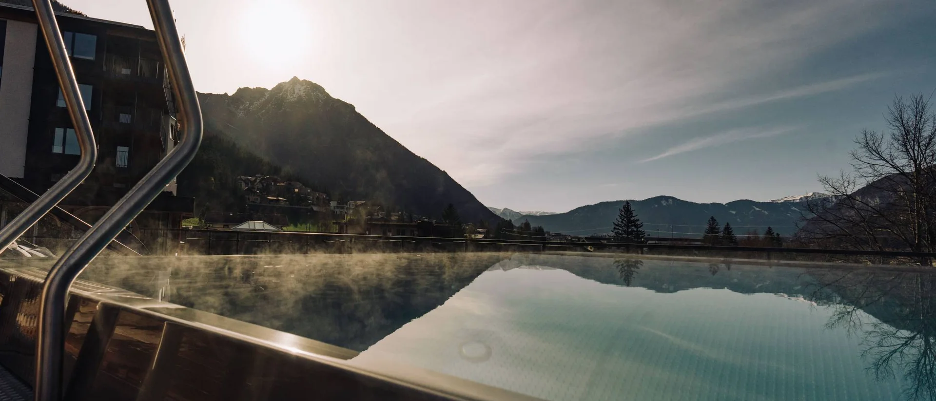 Dampfendes Schwimmbecken mit Bergblick und Sonnenuntergang im Hintergrund