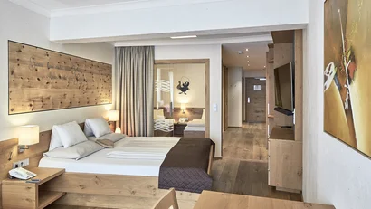 Modernes Hotelzimmer mit Holzdekor, Doppelbett und Fernseher an der Wand