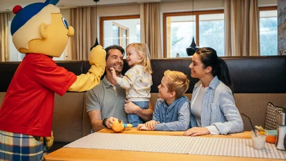 Familie trifft eine Person im bunten Kostüm in einem Restaurant