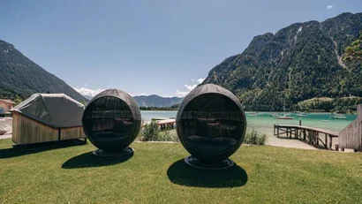 Zwei runde Outdoor-Sessel auf einer Wiese mit Berg- und Seeblick