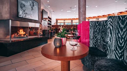 Gemütliche Hotelbar mit Kamin, Tisch, Dekoration und bunten Sitzbänken